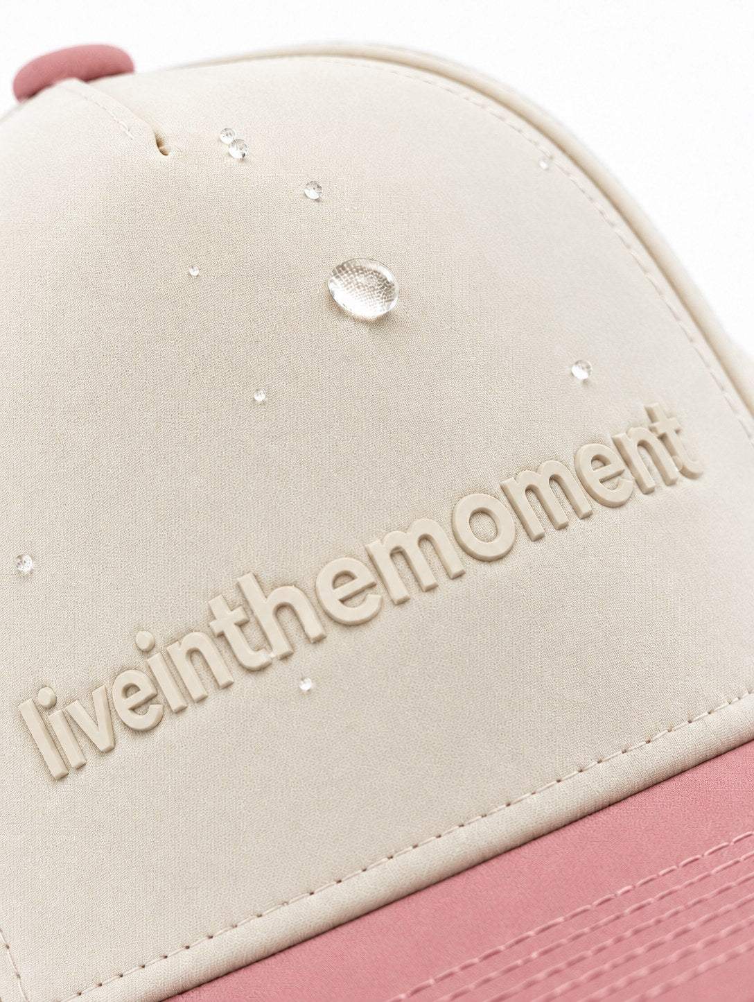 Water droplets beading on the ivory MOJA Kids Live in the Moment cap with a dusty pink brim