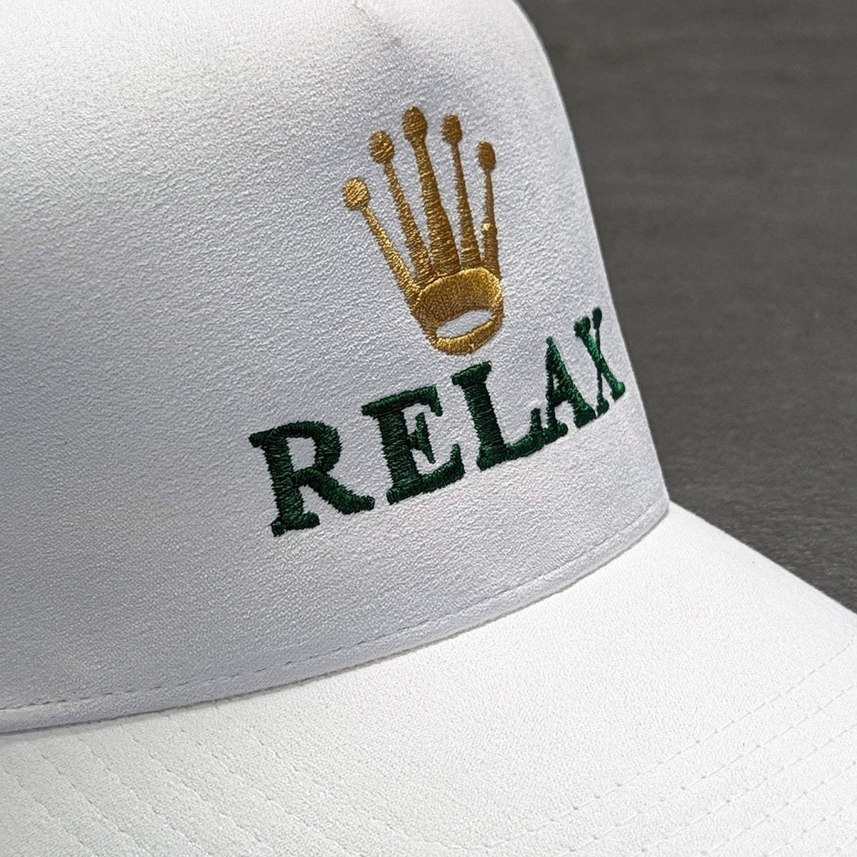 Relax - Premium Suede Snapback Hat in white with gold crown embroidery and dark green RELAX lettering on the front.