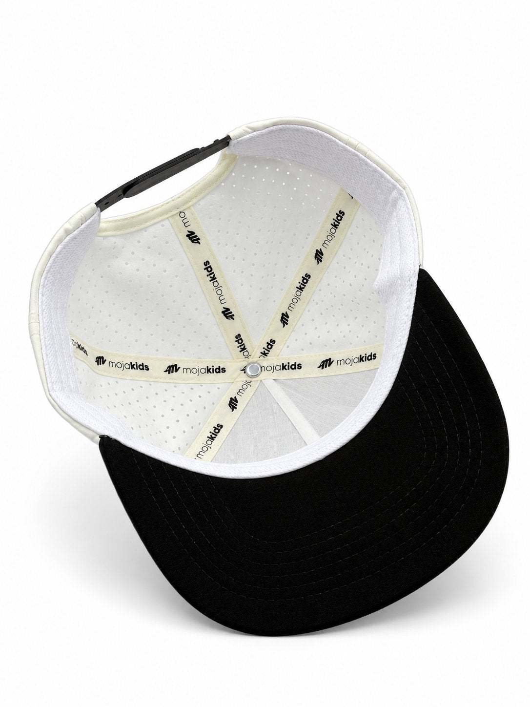 Ivory and black MOJA Kids cap interior showing branded seam tape and laser-cut ventilation