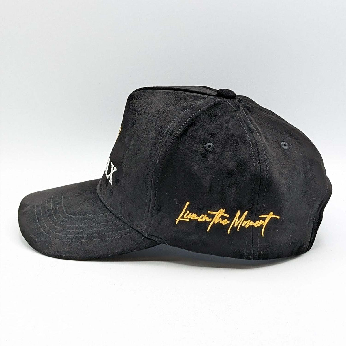 Relax - Premium Suede Snapback Hat in black suede-like fabric, with gold “Live in the Moment” embroidery and curved brim